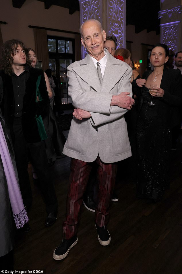 Legendary filmmaker John Waters — known for Hairspray (1988) and Cry Baby (1990) — suited up for the occasion in LA in a gray jacket, a white button-up shirt and patterned maroon dress pants