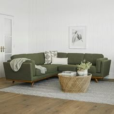 a living room with white walls and wood flooring is pictured in this image, the couches are green