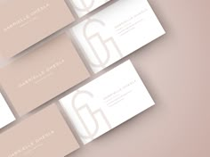 four business cards with the letter g in white and light pink on them, sitting next to each other