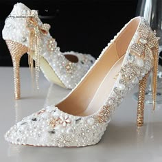 a pair of high heeled shoes with pearls and bows on the heels are sitting next to each other