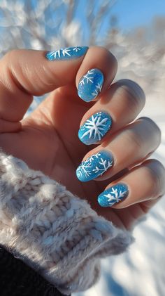 A manicured hand with icy blue nails with white snowflake designs representing Elsa from Frozen. Snowflake Nail Art Designs, Frozen Theme Nails, Frozen Nails Disney, Winter Blue Nail Designs, Disney Winter Nails, Winter Disney Nails, Xmas Nails Blue, Winter Nails With Snowflakes, Snowflake Nails Blue