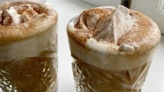 two iced drinks sitting next to each other on top of a white tablecloth covered window sill