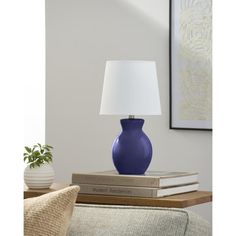 a blue vase sitting on top of a stack of books next to a white lamp