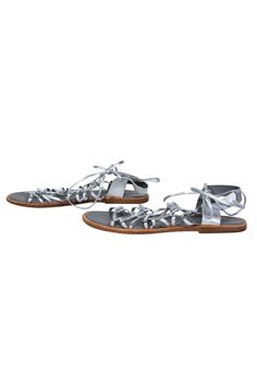Go gladiator glam with these shiny sandals from Vince! Created with a flashy silver metallic design, these strappy beauties are perfect for bringing some glitz to your next big music music festival. Show up to the stage with some Coachella couture vibes when you pair these statement shoes with a flowy sundress and wide brim hat. Size 8.5 Leather upper w/ strappy design Lace-up closure at ankle Round toe Rubber sole and wooden footbed w/ some wear Length 10.75" Silver Summer Party Sandals, Silver Sandals For Summer Party, Metallic Silver Open Toe Sandals For Summer, Glamorous Silver Sandals For Summer, Glamorous Metallic Silver Open Toe Sandals, Silver Ankle Strap Sandals For Spring, Metallic Ankle Strap Sandals For Summer, Glamorous Adjustable Sandals For Spring, Adjustable Glamorous Sandals For Spring