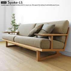 a couch sitting on top of a hard wood floor next to a plant in a vase