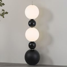 three black and white balls on top of each other in front of a gray wall