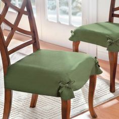 two wooden chairs with green covers on them in front of a window and ruged floor