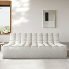 a white couch sitting in front of a window on top of a carpeted floor