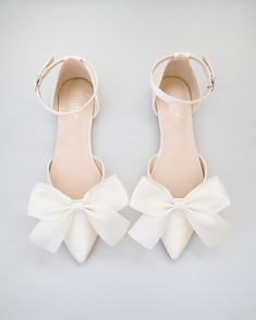 a pair of white shoes with bows on them