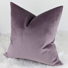 a purple pillow sitting on top of a fluffy white blanket