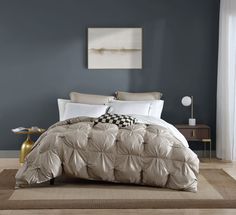 a bedroom with blue walls and a bed covered in a beige comforter, checkered pillow