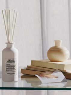 a table topped with books and a white vase filled with reeds