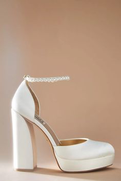 a pair of white high heeled shoes with a beaded ankle tie on top