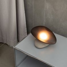 a table lamp sitting on top of a white counter next to a curtained window