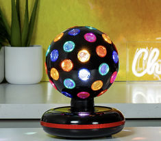 a colorful light up ball sitting on top of a table next to a potted plant