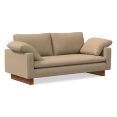 a beige couch with two pillows on the armrests and one pillow sitting on top of it