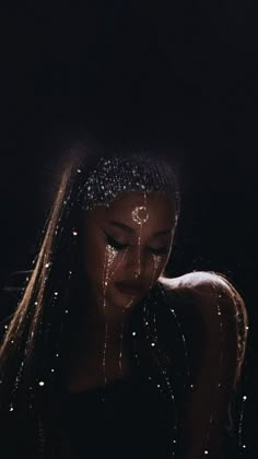 a woman with glitter on her face and long hair is looking down at the ground