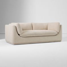 a beige couch sitting on top of a white floor