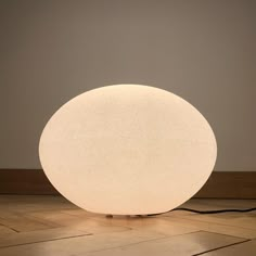 a large white light sitting on top of a wooden floor