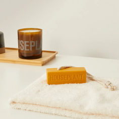 a soap bar sitting on top of a white towel next to a cup and tray