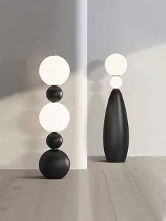 three black and white vases sitting next to each other on a wooden floor in an empty room