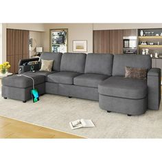 a living room with a sectional couch and ottoman in it's center area, next to a coffee table