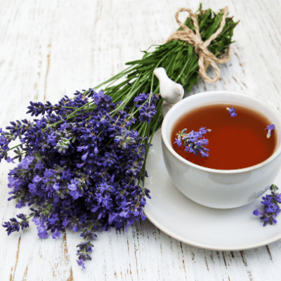 cup of tea in white cup and saucer purple flowers on table