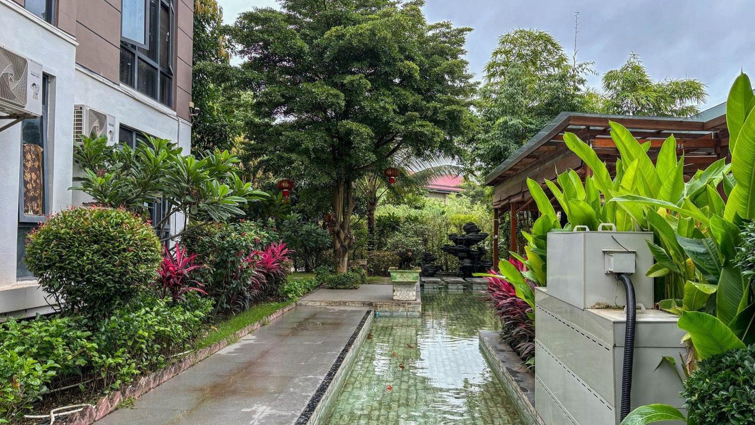 A view of the villa that is being used by He Yingxiong who is currently running Shwe Kokko. The house overlooks a lush plants, a water body and overlooks a river and green trees on the other side
