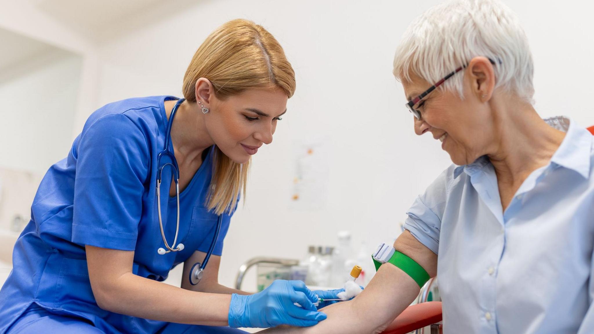 A doctor performs a blood test on a smiling patient