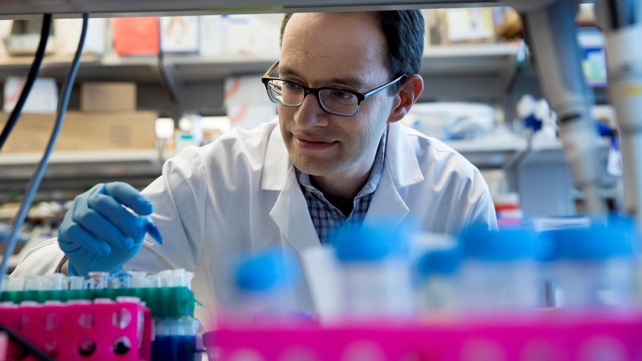 Dr Daniel Heller looks at small test tube 