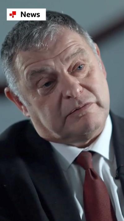 Mike Amesbury wearing a black suit and red tie during an interview