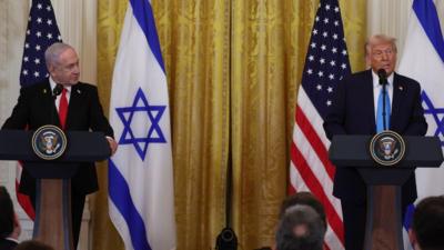 Benjamin Netanyahu and Donald Trump stand side by side at podiums in front of US and Israeli flags.