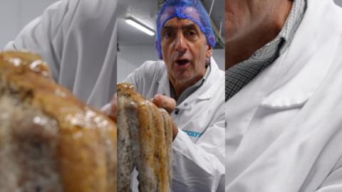 Justin Rowlatt wearing a white coat and a blue net on his head holding a octopus.