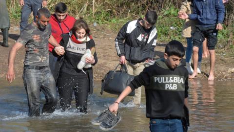 Alawite Syrians, who fled the violence in western Syria, cross the Nahr el-Kabir river in Akkar, Lebanon (11 March 2025)