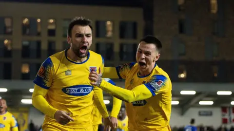 Josh Rees celebrates giving Dagenham & Redbridge the lead at AFC Wimbledon