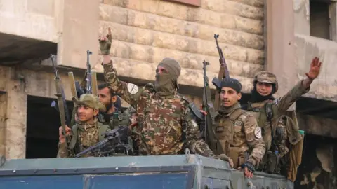 Anti-government fighters celebrate in a street in Maaret al-Numan in Syria's northwestern Idlib province on 30 November 2024.