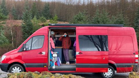 Holly McHugh inside her campervan drinking a cup of tea