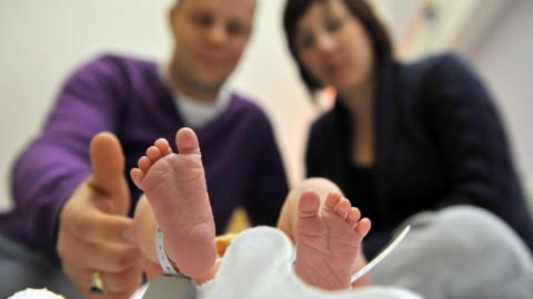 A close up of a newborn's feet in focus with parents looking down out of focus behind.