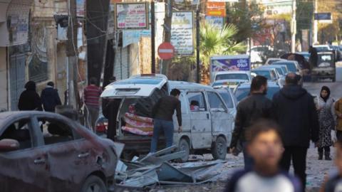 People walk past a damaged site in Aleppo after air strikes by Russian forces. 