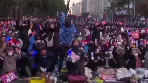 Huge crowd of people with hands raised in the air upon hearing news