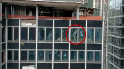 A NYC high-rise building has broken structural beams. In the image, one broken beam is circled in red.