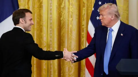 US President Donald Trump and French President Emmanuel Macron shake hands at the end of a joint press conference 