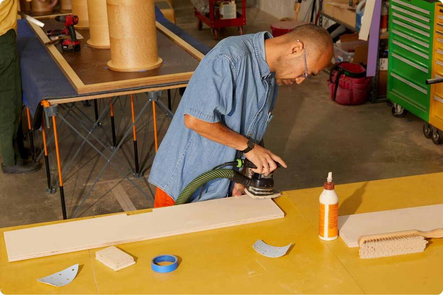 Person sanding down a 2x4 plank of wood.