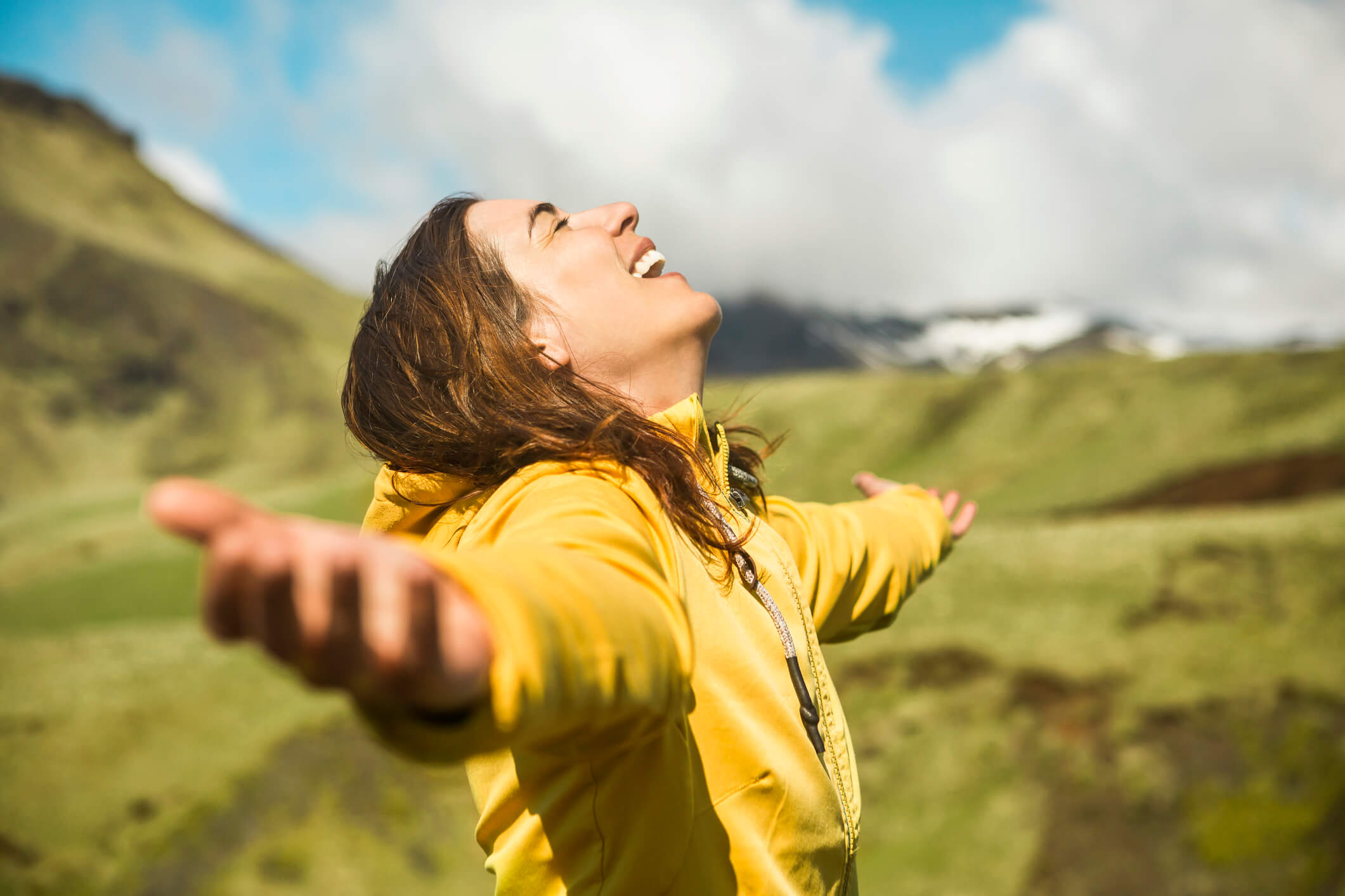 A woman in a yellow jacket with her arms outstretched.