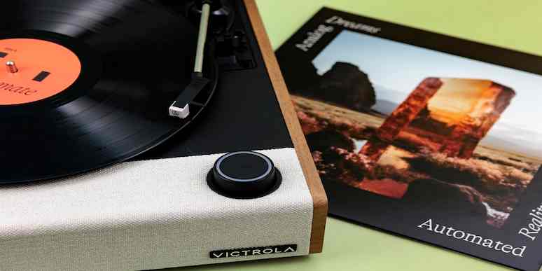 A close-up of a Victrola record player next to a vinyl record sleeve.