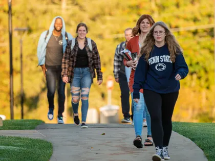 Students walking outside with yellow leaves in background