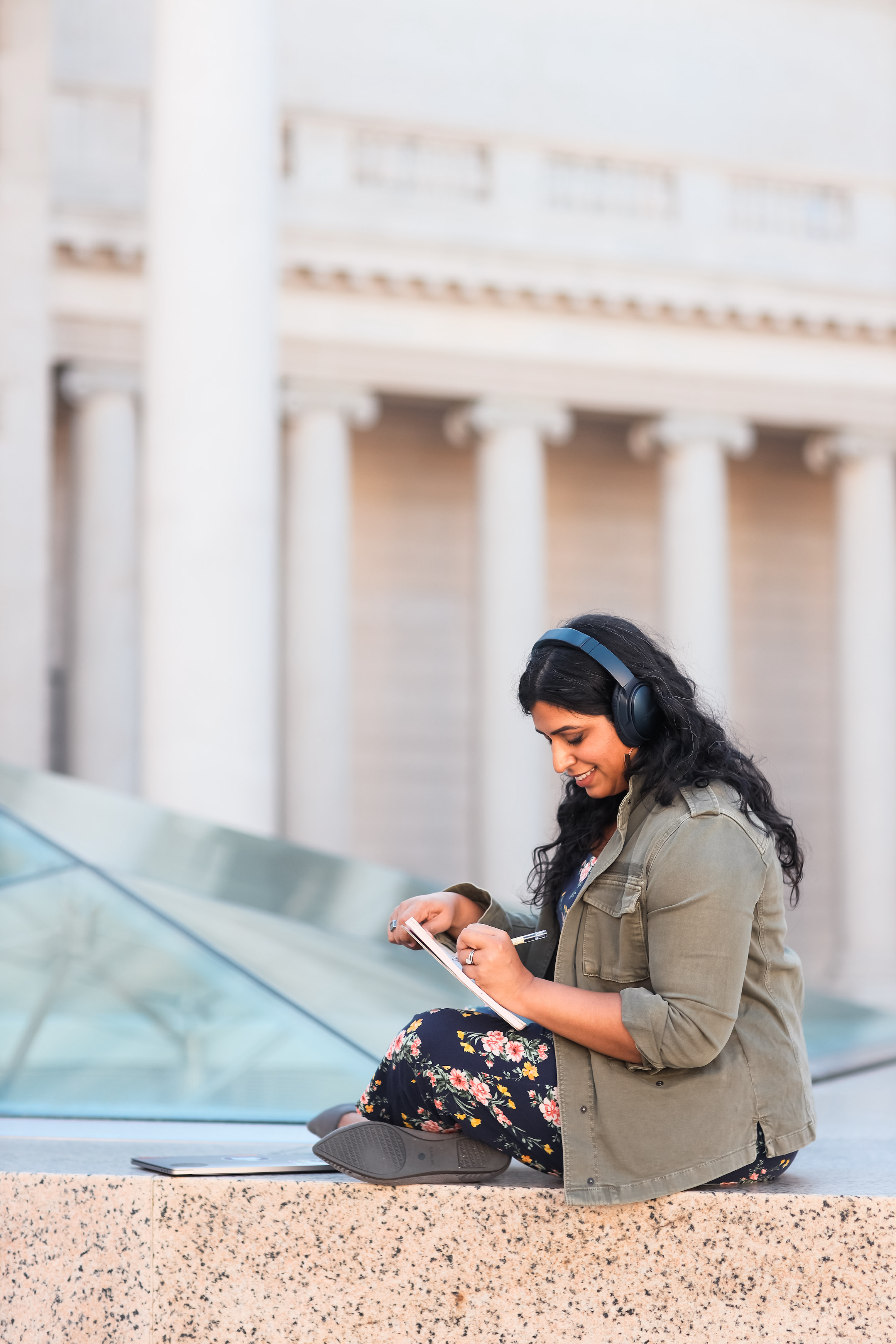 Author Neha sitting outside with headphones on, working on a tablet