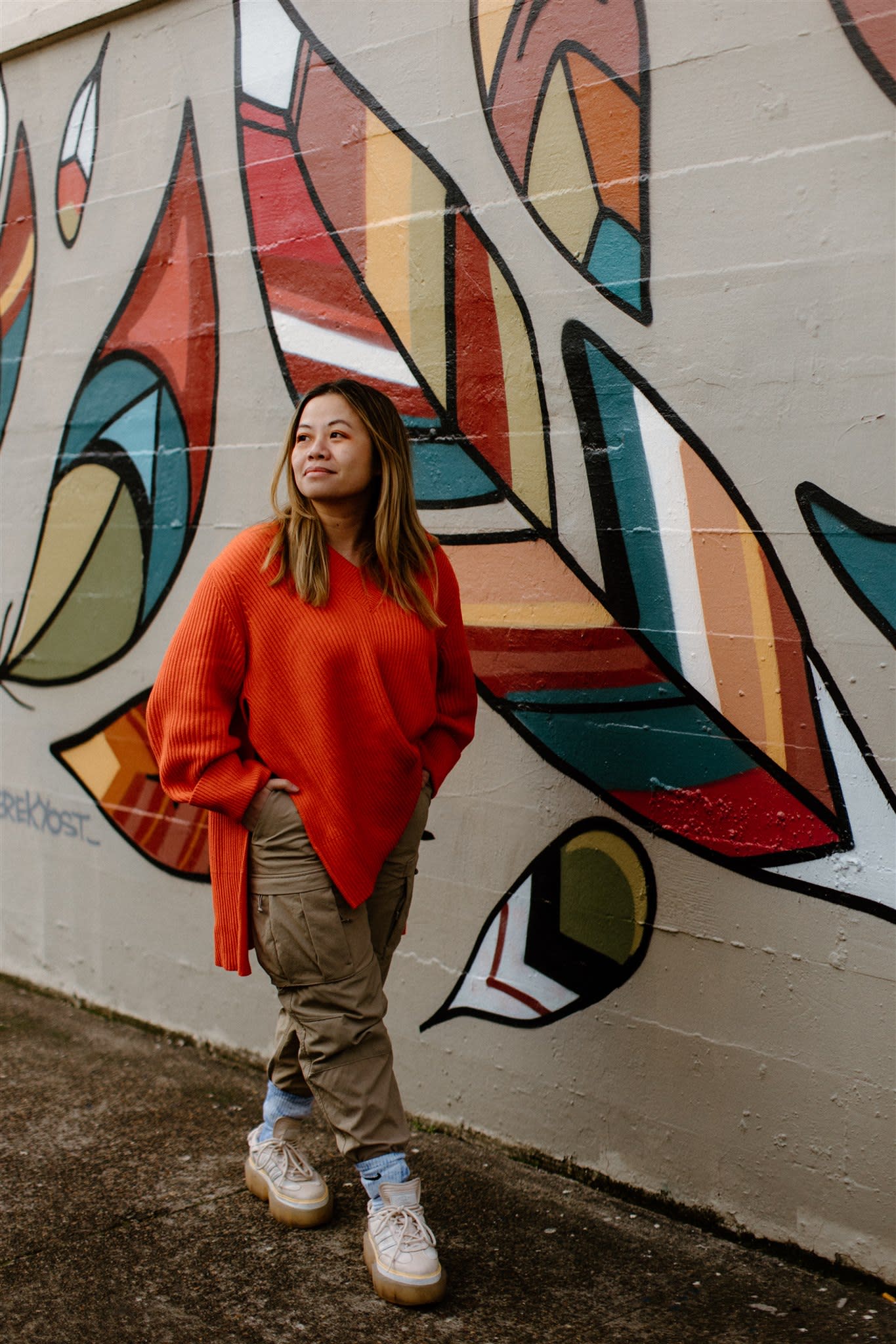 Author Tatiana walking outside in front of a colorful mural