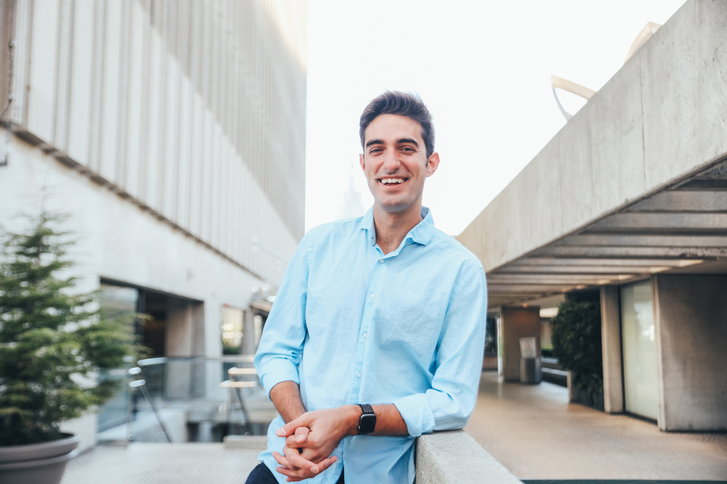 Author Feross smiling and leaning against a concrete wall in an urban space