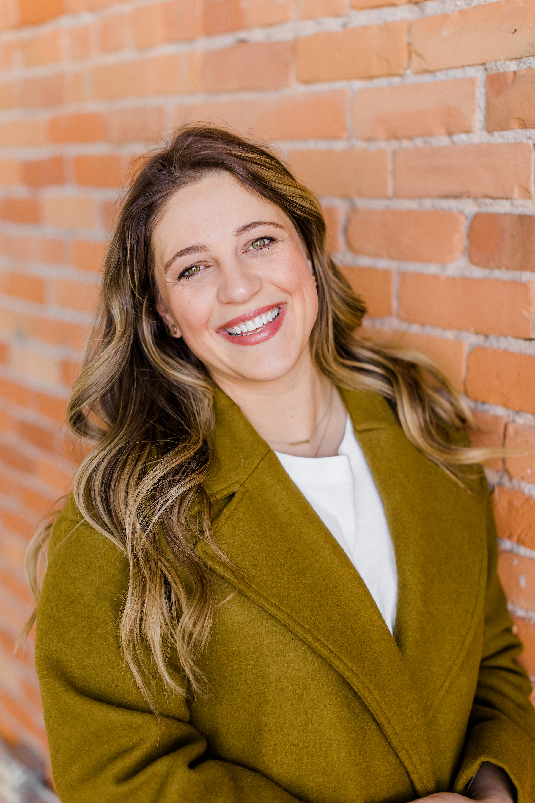 Close-up of author Rose smiling against a brick wall backdrop